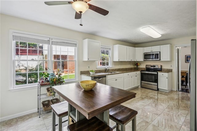 kitchen featuring baseboards, a sink, white cabinetry, and stainless steel appliances