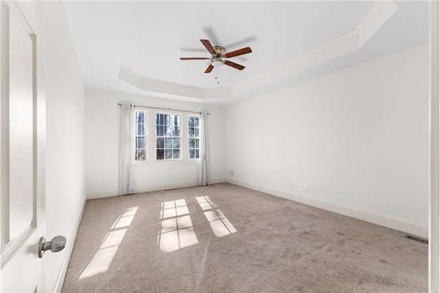 spare room featuring visible vents, baseboards, a raised ceiling, a ceiling fan, and carpet floors