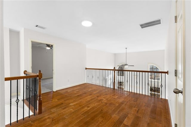 empty room with baseboards, visible vents, ceiling fan, and wood finished floors