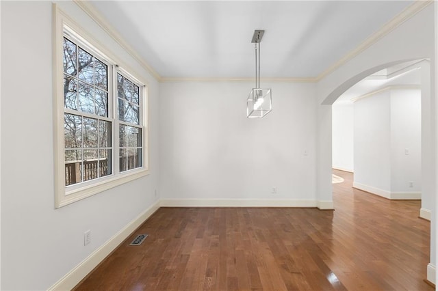 unfurnished dining area with baseboards, arched walkways, wood finished floors, and ornamental molding