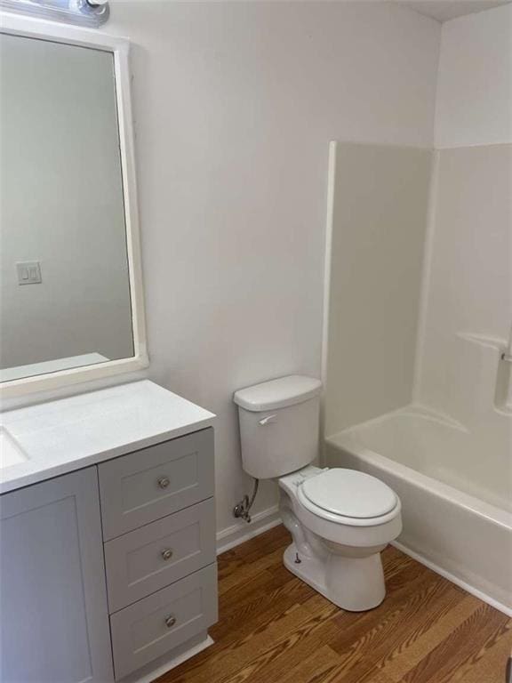 full bathroom featuring hardwood / wood-style flooring, shower / bathtub combination, vanity, and toilet