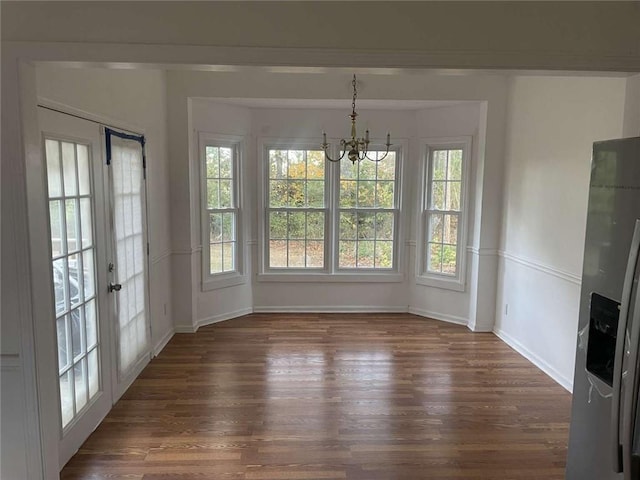 unfurnished dining area featuring a notable chandelier and dark hardwood / wood-style flooring