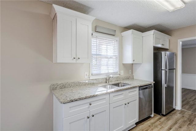 kitchen featuring white cabinetry, stainless steel appliances, light stone counters, and sink