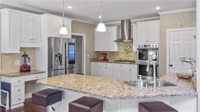 kitchen featuring a sink, a kitchen bar, wall chimney range hood, and stainless steel appliances