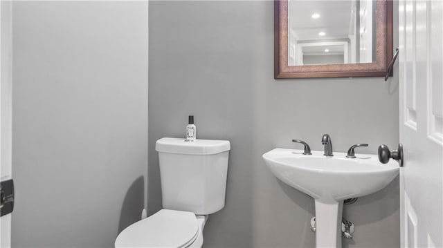 half bath featuring recessed lighting, a sink, and toilet