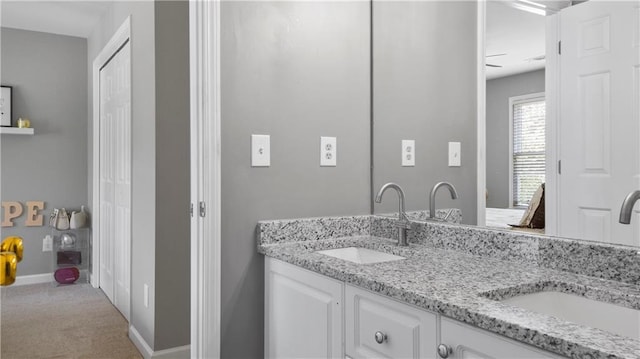 bathroom featuring double vanity, baseboards, and a sink