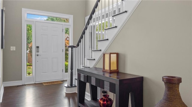 foyer with dark wood-style flooring, visible vents, a towering ceiling, stairway, and baseboards