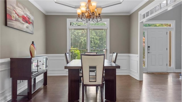dining room featuring an inviting chandelier, ornamental molding, a decorative wall, and dark wood-style flooring