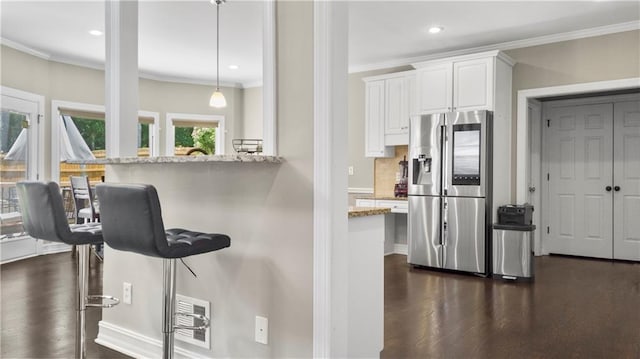 kitchen with crown molding, stainless steel fridge with ice dispenser, a breakfast bar, and dark wood-type flooring