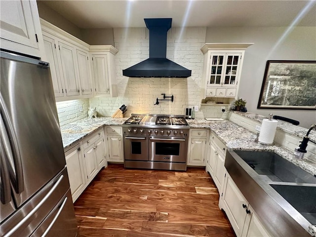 kitchen featuring white cabinetry, wall chimney exhaust hood, appliances with stainless steel finishes, and dark hardwood / wood-style floors