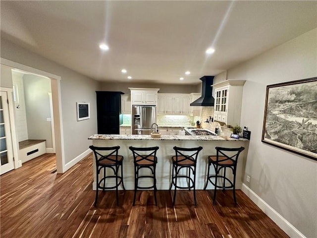 kitchen featuring stainless steel fridge, premium range hood, dark wood-type flooring, and kitchen peninsula