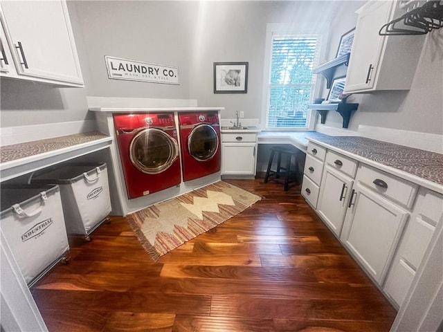 laundry area with sink, dark wood-type flooring, washer and clothes dryer, and cabinets