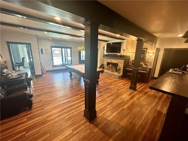 game room with a stone fireplace, billiards, and hardwood / wood-style floors