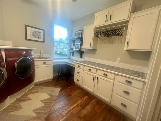 laundry area with dark wood-type flooring, washing machine and dryer, cabinets, and sink