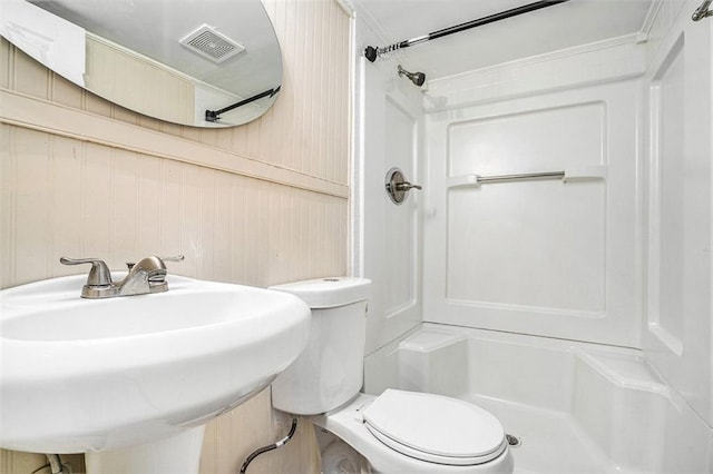 bathroom featuring toilet, walk in shower, wooden walls, and sink