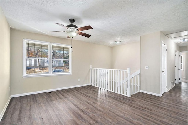 spare room with a textured ceiling, ceiling fan, and dark wood-type flooring