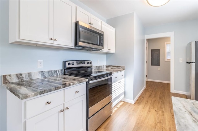 kitchen featuring electric panel, light stone countertops, appliances with stainless steel finishes, light hardwood / wood-style floors, and white cabinetry