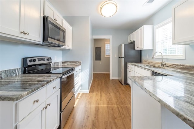 kitchen featuring white cabinetry, sink, light stone counters, light hardwood / wood-style floors, and appliances with stainless steel finishes