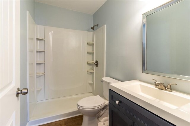 bathroom featuring toilet, vanity, hardwood / wood-style floors, and walk in shower