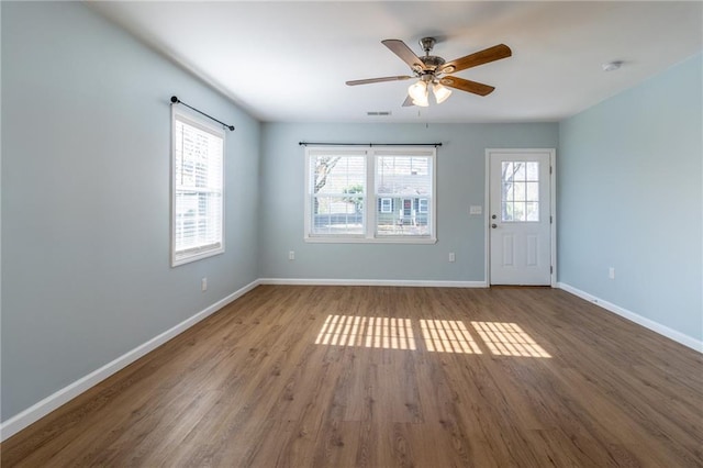 empty room featuring ceiling fan, hardwood / wood-style floors, and a healthy amount of sunlight