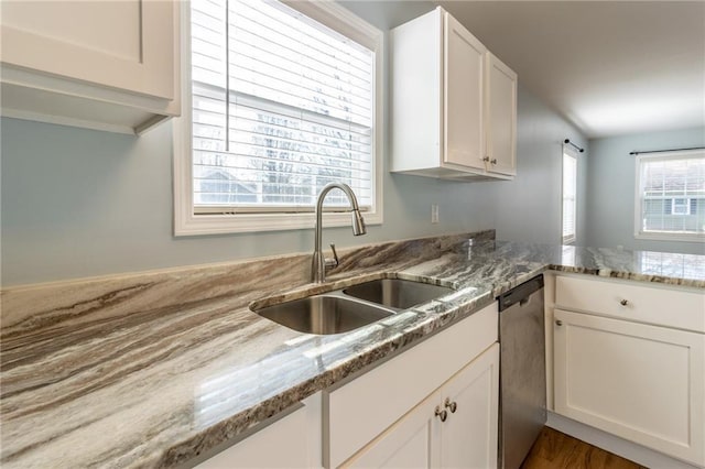 kitchen featuring dishwasher, sink, light stone counters, and plenty of natural light