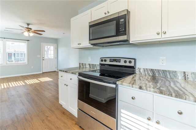 kitchen with ceiling fan, appliances with stainless steel finishes, light hardwood / wood-style floors, light stone counters, and white cabinetry