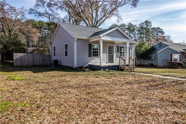 bungalow-style home featuring cooling unit, covered porch, and a front yard