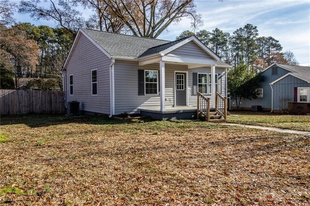 bungalow with a porch, central air condition unit, and a front yard