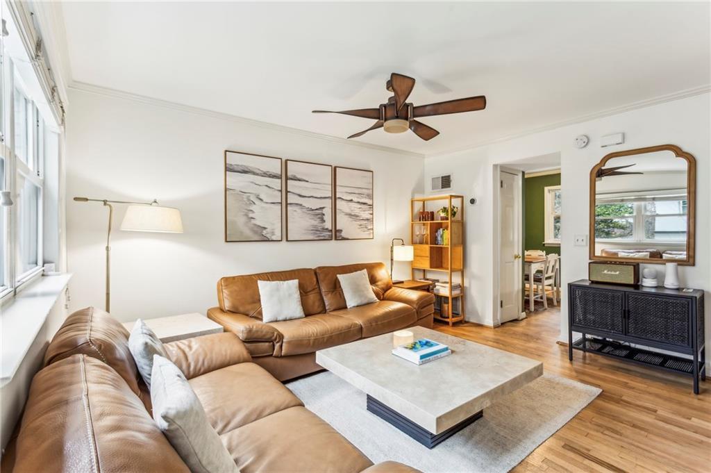 living room with light hardwood / wood-style flooring, ornamental molding, and ceiling fan