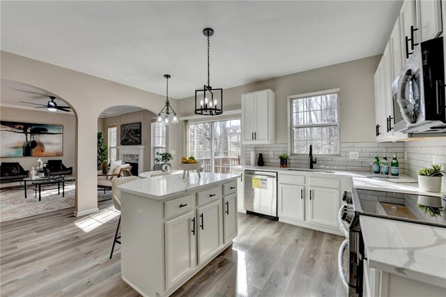 details featuring stainless steel electric stove, light stone countertops, light wood-type flooring, and white cabinets