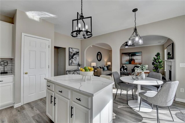 kitchen with pendant lighting, dishwasher, a center island, a wealth of natural light, and light stone countertops