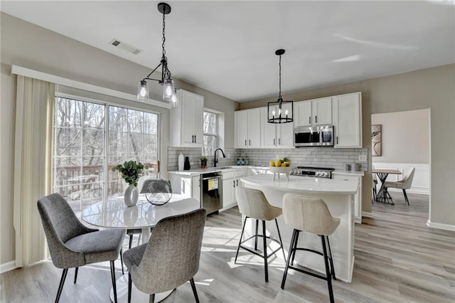 kitchen featuring light countertops, stainless steel microwave, visible vents, a sink, and dishwasher