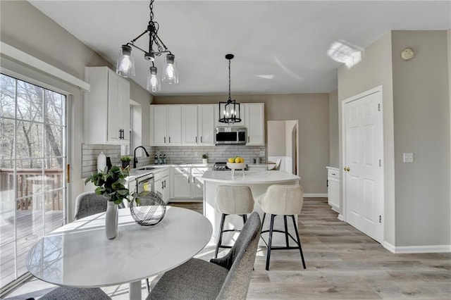 kitchen with tasteful backsplash, white cabinets, a kitchen island, stainless steel appliances, and light countertops