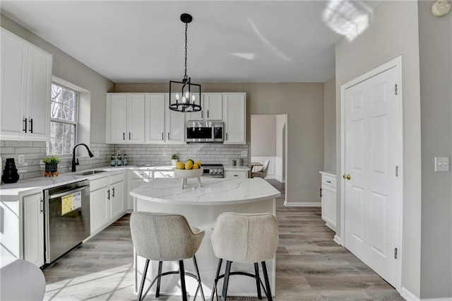 kitchen featuring decorative backsplash, appliances with stainless steel finishes, light stone counters, and a sink