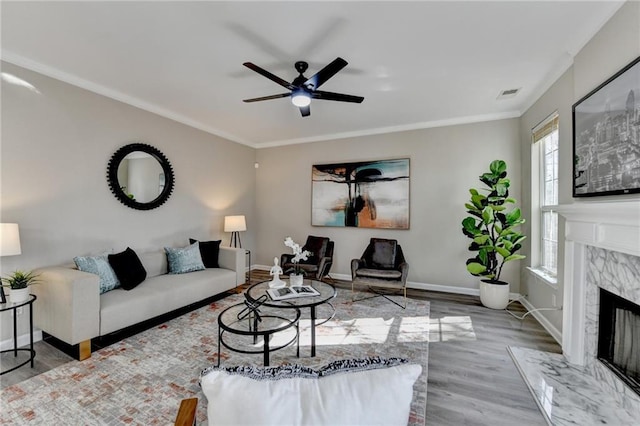 living room with crown molding, visible vents, a fireplace, and baseboards