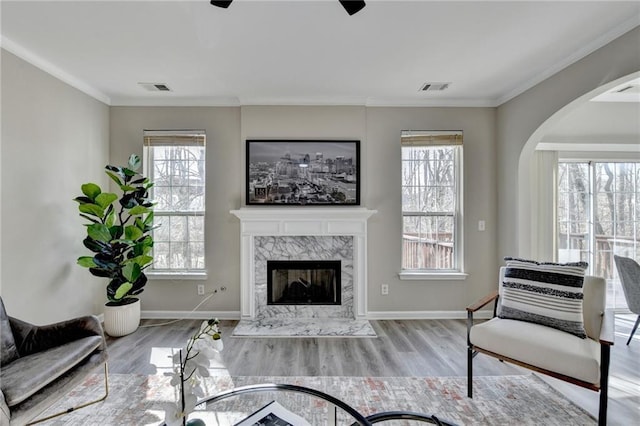 living area featuring a high end fireplace, visible vents, and crown molding