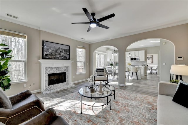 living area with a premium fireplace, visible vents, arched walkways, and ornamental molding