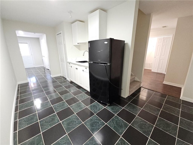 kitchen with black refrigerator, sink, dark tile patterned floors, and white cabinets