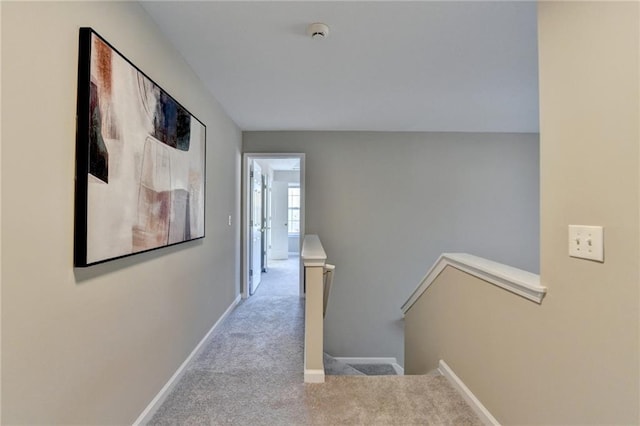 corridor featuring carpet, baseboards, and an upstairs landing