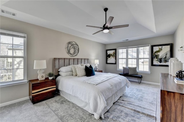 bedroom with a tray ceiling, carpet flooring, visible vents, and baseboards