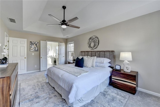 bedroom featuring light carpet, a raised ceiling, visible vents, and baseboards