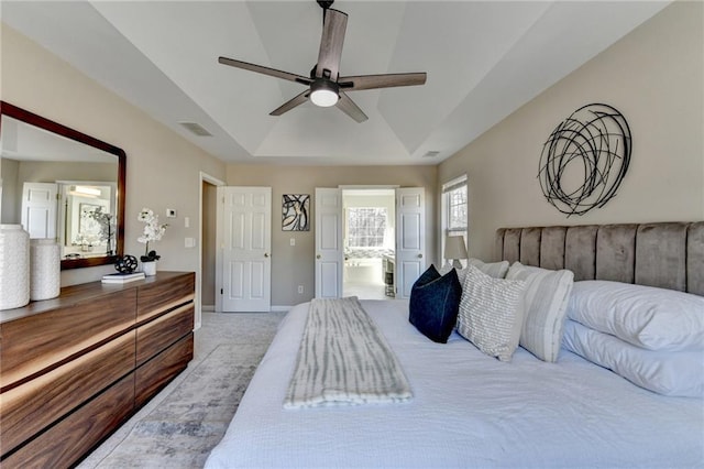 bedroom featuring baseboards, visible vents, and a tray ceiling