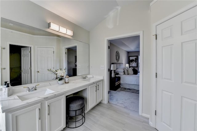 ensuite bathroom with double vanity, connected bathroom, and a sink