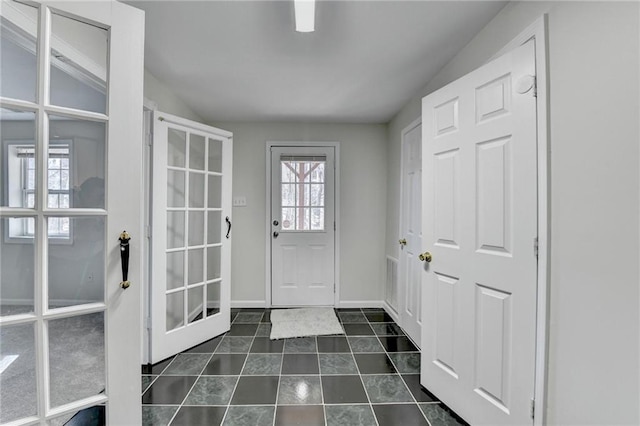 doorway with dark tile patterned floors and baseboards