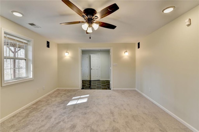 empty room featuring a ceiling fan, carpet, visible vents, and baseboards