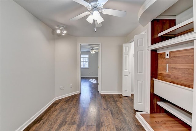 interior space featuring dark wood-type flooring, a ceiling fan, and baseboards