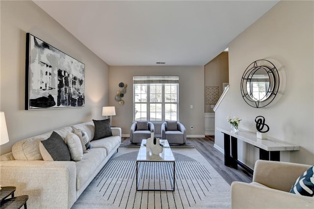 living room with baseboards, visible vents, and wood finished floors