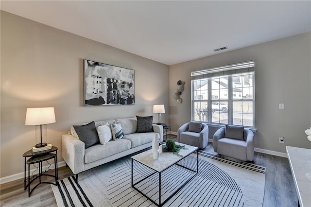 living room with visible vents, baseboards, and wood finished floors