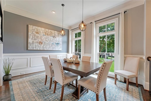 dining area with a decorative wall, dark wood-style flooring, crown molding, and wainscoting