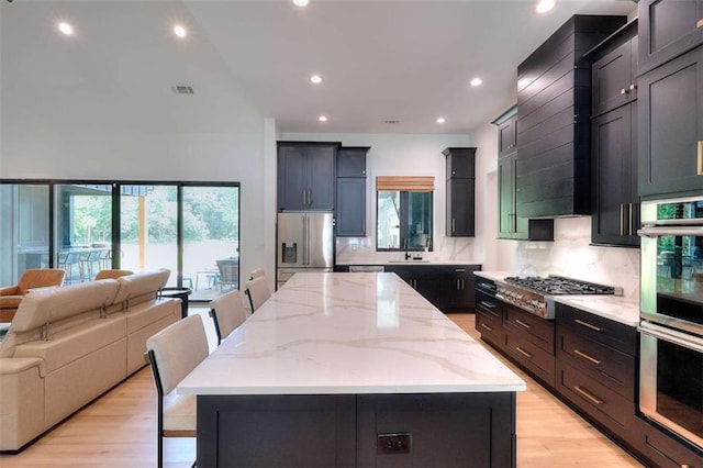 3960 Stock Rd, Monroe, GA 30656 - kitchen featuring appliances with stainless steel finishes, open floor plan, tasteful backsplash, a kitchen island, and light stone countertops